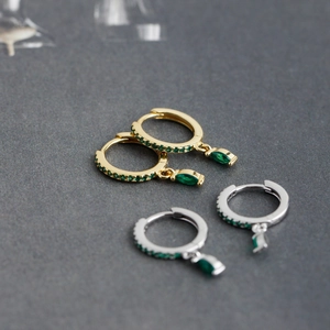 Detailed macro view of S925 silver huggie earrings with marquise cut green zircon stones