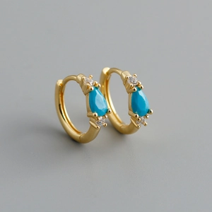 Detailed macro of gold hoop earrings with pear-shaped turquoise and cubic zirconia accents