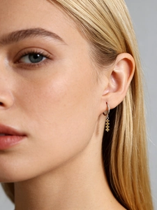 Gros plan de boucles d'oreilles pendantes en argent avec trois zircons jaunes gradués