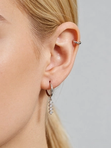Gros plan de créoles en argent serties de zircons cubiques verticaux sur l'oreille
