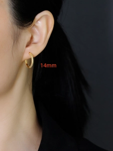 Detail van 14mm gouden oorring met kralentextuur gedragen door een model