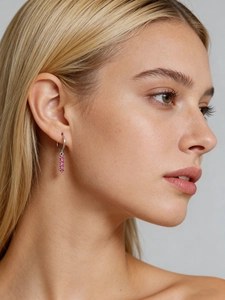 Gros plan de boucles d'oreilles créoles en argent avec trois zircons roses sur un mannequin