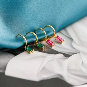 Détail de boucles d'oreilles dorées avec cristaux rectangulaires vert émeraude et rose