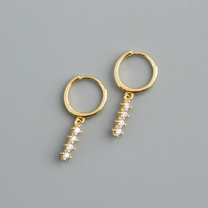Vue macro de boucles d'oreilles créoles dorées avec pendentifs linéaires en zircon blanc