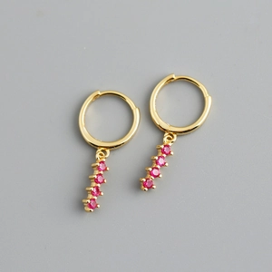 Détail de créoles dorées avec pendentifs verticaux sertis de zircons roses