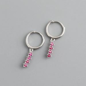 Détail macro de boucles d'oreilles créoles en argent avec rangées de zircons roses