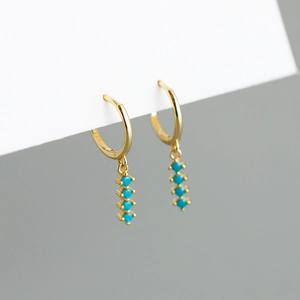 Gros plan détaillé sur créoles en argent S925 doré avec quatre perles turquoise pendante