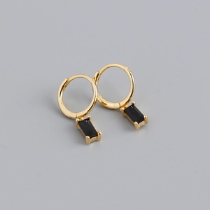 Gros plan sur des boucles d'oreilles dorées avec un zircon noir rectangulaire