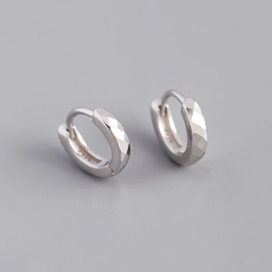 Macro-opname van S925 sterling zilveren huggie oorbellen met gefacetteerde textuur