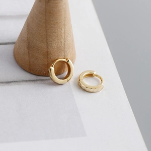 Detailopname van gouden geometrische oorringen op een minimalistische houten standaard