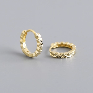 Detail view of gold-plated S925 sterling silver huggie earrings with diamond-cut pattern