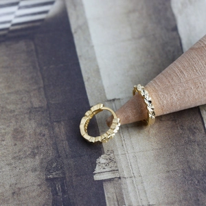 Macro detail of S925 sterling silver stamp on diamond-cut gold-plated hoop earrings