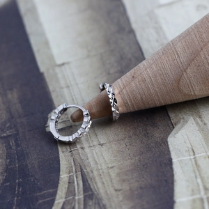 Detailed macro view of S925 sterling silver hoop earrings with diamond-cut textured surface