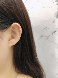 Detail of twisted gold ear cuff on model ear, minimalist S925 silver jewelry design
