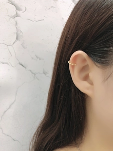 Close-up of golden twisted rope ear cuff on model ear showing woven texture