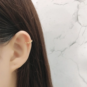 Minimalist twisted gold cuff earring for women shown on ear in a stylish side view