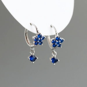 Détails macro des créoles en argent S925 avec pendentif fleur en zircone bleue