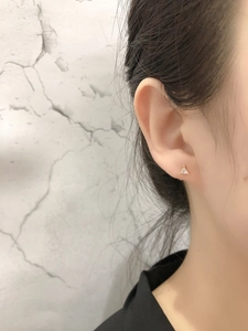 Vue détaillée d'une boucle d'oreille triangle dorée avec zircon clair sur l'oreille