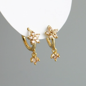 Gros plan sur des boucles d'oreilles fleurs en argent S925 doré avec zircons champagne