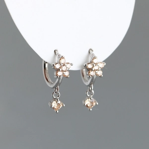Détail du poinçon S925 sur des boucles d'oreilles fleur avec des zircons champagne