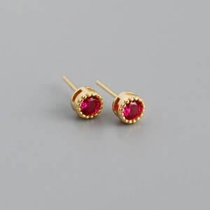 Détail de boucles d'oreilles en zircon rouge avec monture couronne dorée vintage