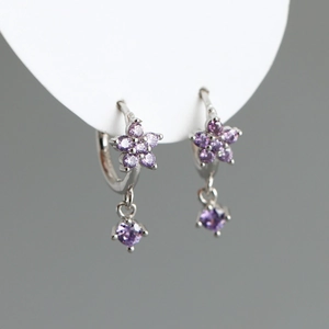 Détail macro de boucles d'oreilles fleur de prunier avec zircons violets sur support