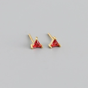 Vue rapprochée des boucles d'oreilles triangulaires dorées avec cristaux de zircon rouge