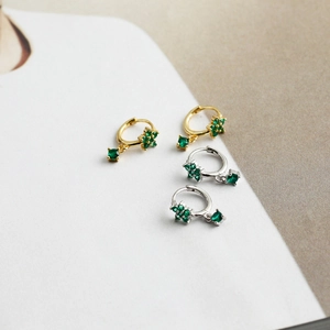 Détail macro de boucles d'oreilles créoles S925 avec pendentifs fleurs en zircon vert