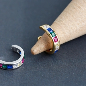 Makro-Detail von Ohrklemmen aus Gold und Silber mit bunten Regenbogen-Edelsteinen