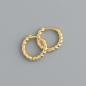 Detail of gold twisted rope hoop earrings with a polished metallic spiral texture