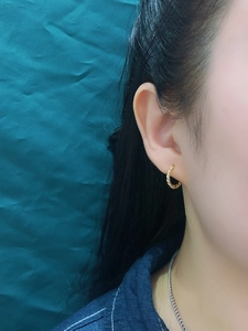Detail of gold twisted hoop earrings showing refined spiral texture on female model