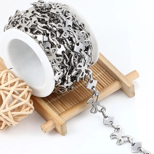 Macro detail of silver hollow butterfly metal chain on white spool for DIY jewelry crafts