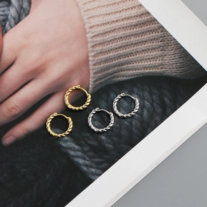 Detail of twisted rope hoop earrings in gold and silver finish on lifestyle magazine