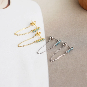 Detail view of gold and silver S925 earrings with turquoise beads and tassel chains