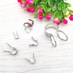 Various sizes of polished stainless steel bail clasps and jewelry connectors on wood