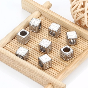 Square stainless steel letter beads for DIY jewelry making on a bamboo tray