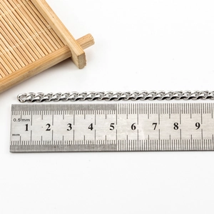 Silver 5mm polished stainless steel curb chain being measured with a metal ruler