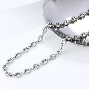 Polished stainless steel coffee bean link chain draped from a bowl on white background