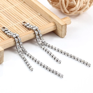 Elegant silver tassel rhinestone earrings with double chains on a bamboo mat background