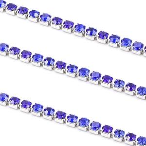 Détail d'une chaîne tennis argentée avec cristaux bleu foncé sertis de quatre griffes