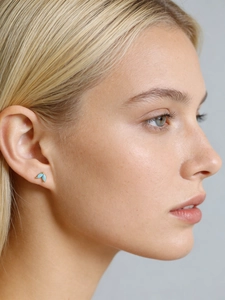 Close-up of minimalist leaf earrings with blue turquoise inlay on gold metal base