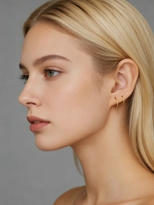 Primer plano de aretes de aro minimalistas en plata S925 bañada en oro sobre una modelo