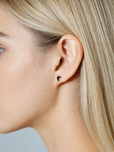 Close-up of a model wearing minimalist silver stud earrings with black V-shaped marquise stone