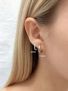 Comparación de tamaños de aros de plata de 9mm y 11mm usados en la oreja de una modelo