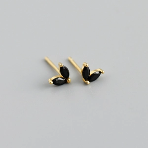Macro detail of gold earrings featuring two black marquise-cut stones in a leaf design