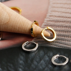 Primer plano de pendientes de aro huggie de plata S925 en oro y plata sobre madera
