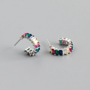 Close-up of C-shaped silver earrings with rainbow rectangular zircon stones