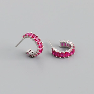 Macro detail of silver hoop earrings with princess cut rose red zircon gemstones