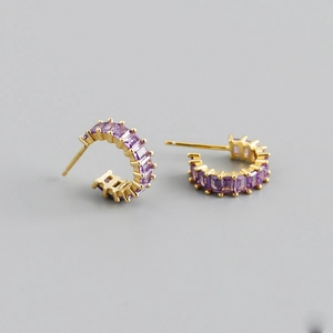 Detail of C-shaped gold-plated earrings with rectangular purple zircon gemstones