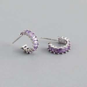 Macro detail of silver C-shaped earrings with purple rectangular baguette cubic zirconia stones